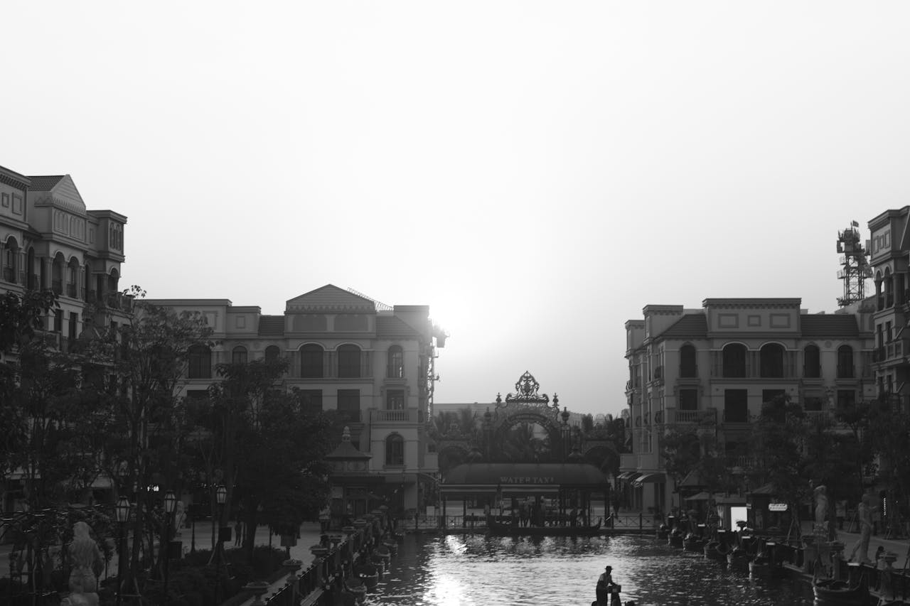 Black and white cityscape with classic architecture and a serene waterfront at dusk.